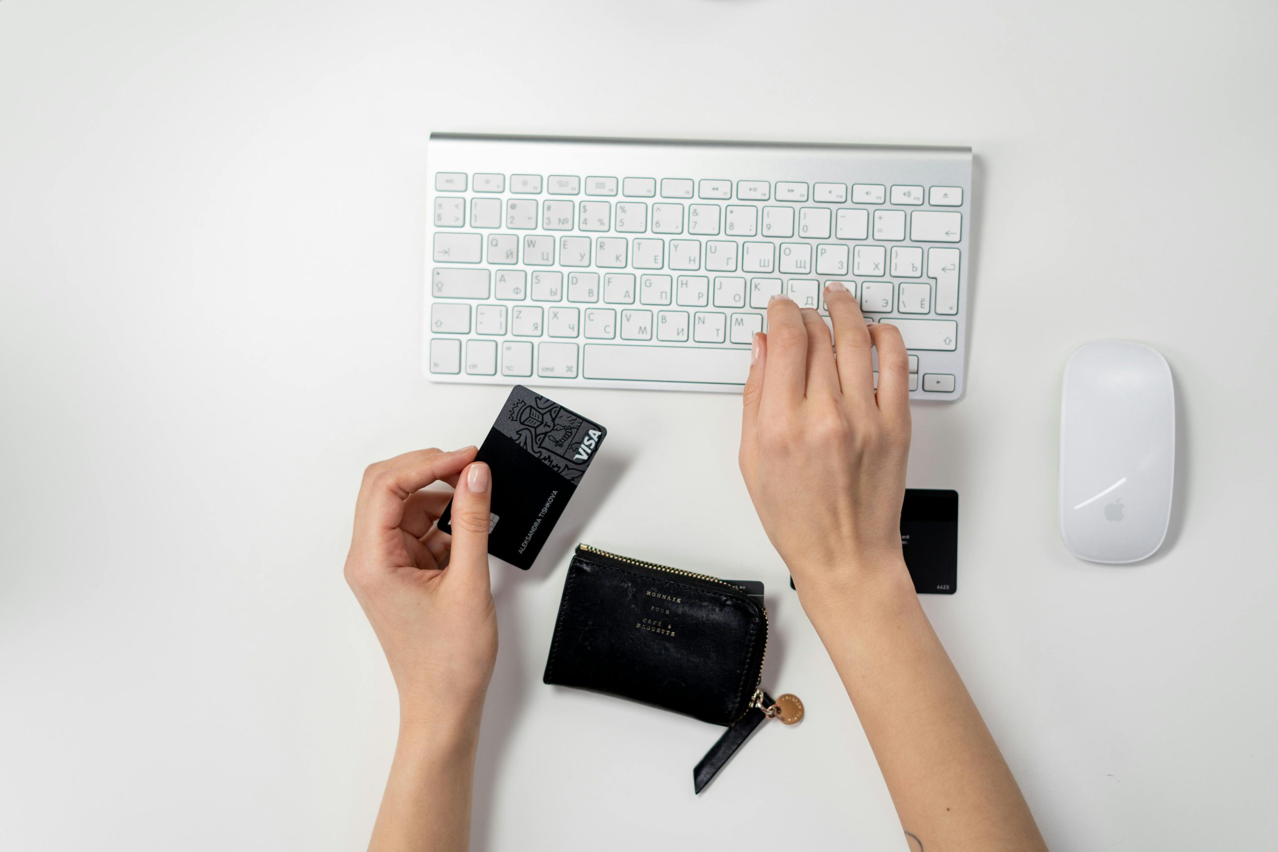 hands typing on a keyboard while holding a credit card